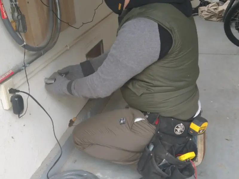 Electrician performing outlet wiring in a White garage